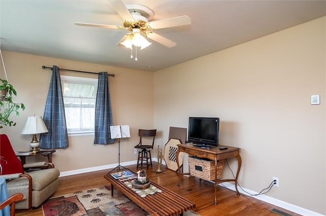 living room featuring baseboards, ceiling fan, and wood finished floors