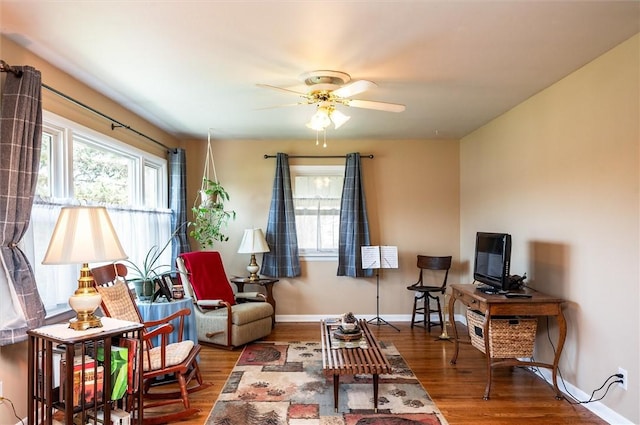 living area featuring a healthy amount of sunlight, baseboards, a ceiling fan, and wood finished floors