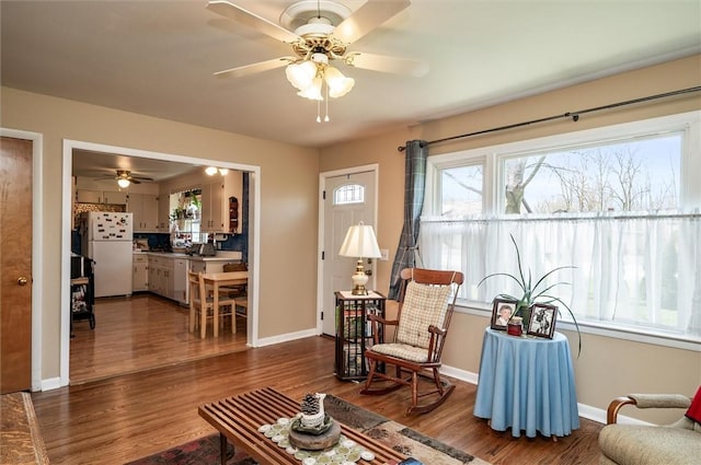 living area with baseboards, ceiling fan, and wood finished floors