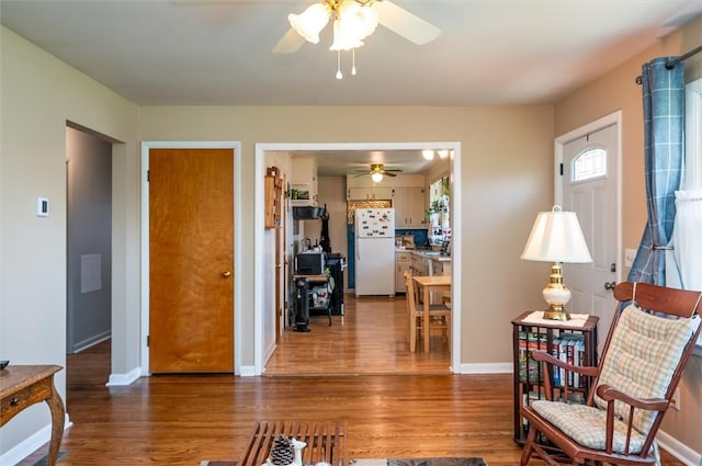 living room with baseboards, ceiling fan, and wood finished floors