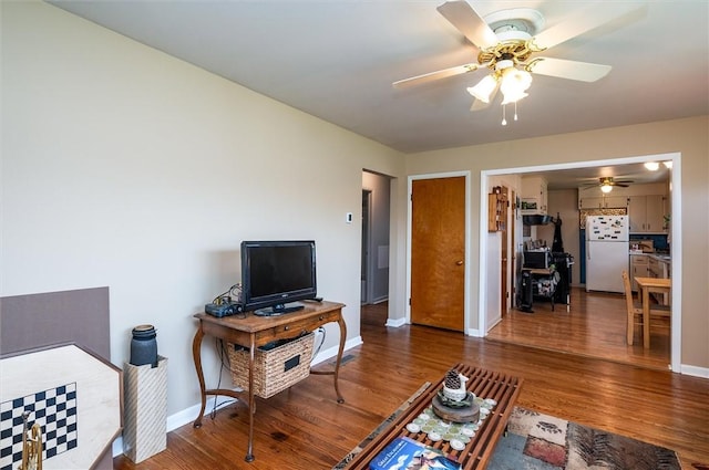 living room with baseboards, a ceiling fan, and wood finished floors