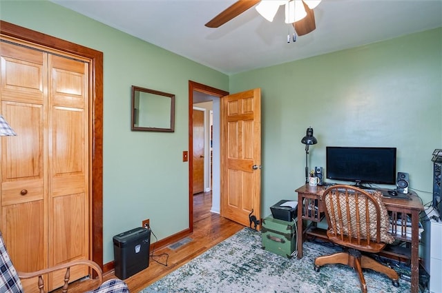 home office featuring a ceiling fan, baseboards, visible vents, and wood finished floors