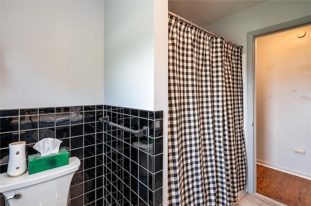 bathroom with toilet, a wainscoted wall, tile walls, wood finished floors, and a shower with curtain