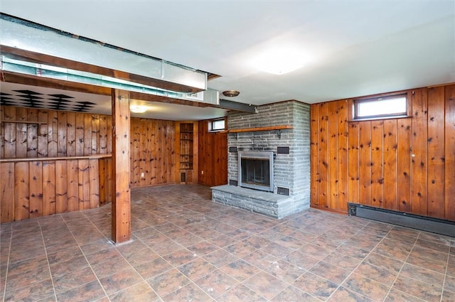 unfurnished living room featuring a brick fireplace, wood walls, and baseboard heating