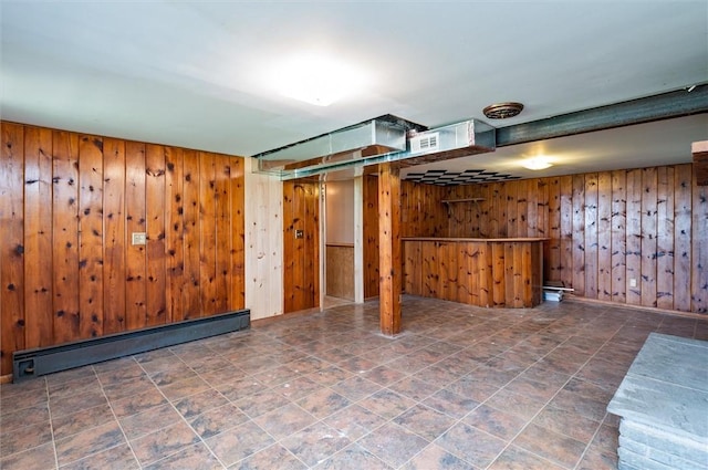 finished basement featuring wooden walls, visible vents, and a baseboard radiator
