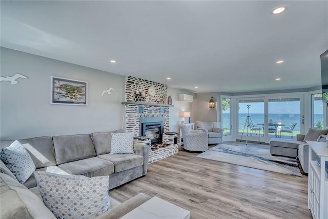 living area featuring light wood-style floors, a brick fireplace, recessed lighting, and a wall mounted air conditioner