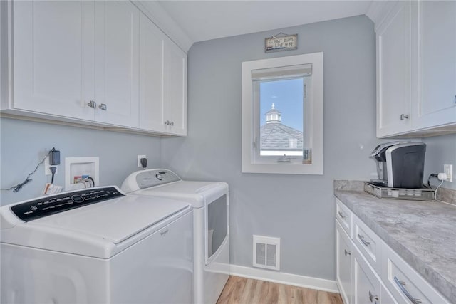 laundry area featuring washing machine and clothes dryer, visible vents, cabinet space, baseboards, and light wood finished floors