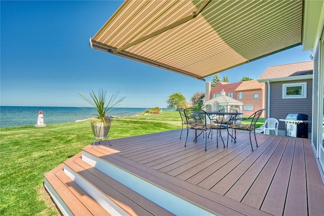 wooden deck with a yard, a water view, outdoor dining space, and area for grilling