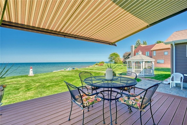 wooden deck with a lawn, a water view, a gazebo, and outdoor dining space