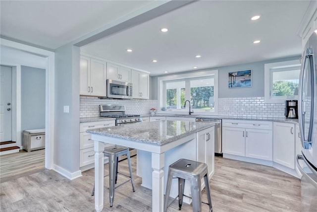 kitchen featuring light wood-style flooring, a kitchen breakfast bar, a healthy amount of sunlight, and stainless steel appliances
