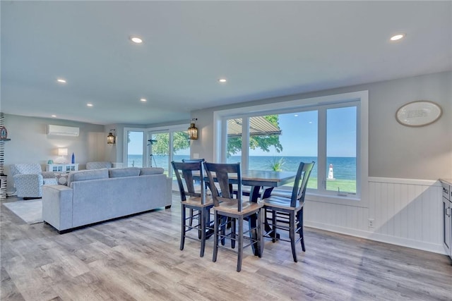 dining area with an AC wall unit, recessed lighting, light wood-type flooring, and a wainscoted wall