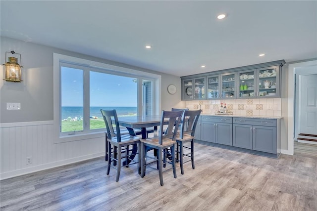 dining area with recessed lighting, a wainscoted wall, and light wood-style floors