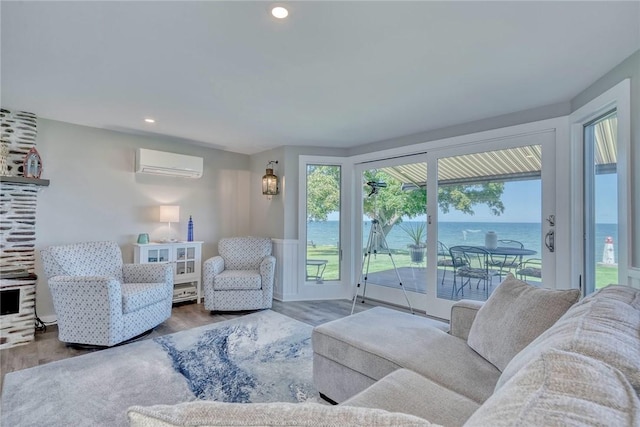 living room with a water view, a wall mounted AC, wood finished floors, and recessed lighting