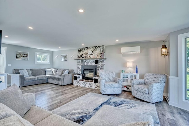 living area with plenty of natural light, a wall mounted air conditioner, wood finished floors, and recessed lighting