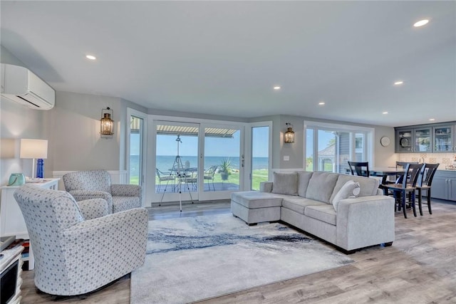 living room with a water view, an AC wall unit, recessed lighting, and wood finished floors