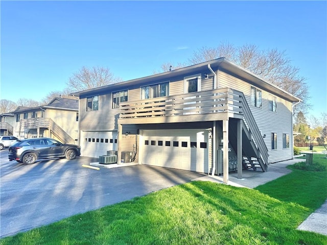 view of front of property featuring aphalt driveway, a garage, stairway, central AC, and a front lawn