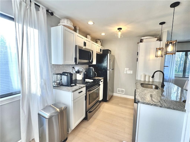 kitchen featuring visible vents, baseboards, a sink, light wood finished floors, and appliances with stainless steel finishes