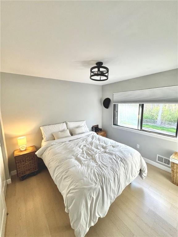 bedroom with visible vents, light wood-style flooring, and baseboards
