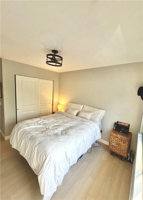 bedroom with a closet, baseboards, and light wood-style floors