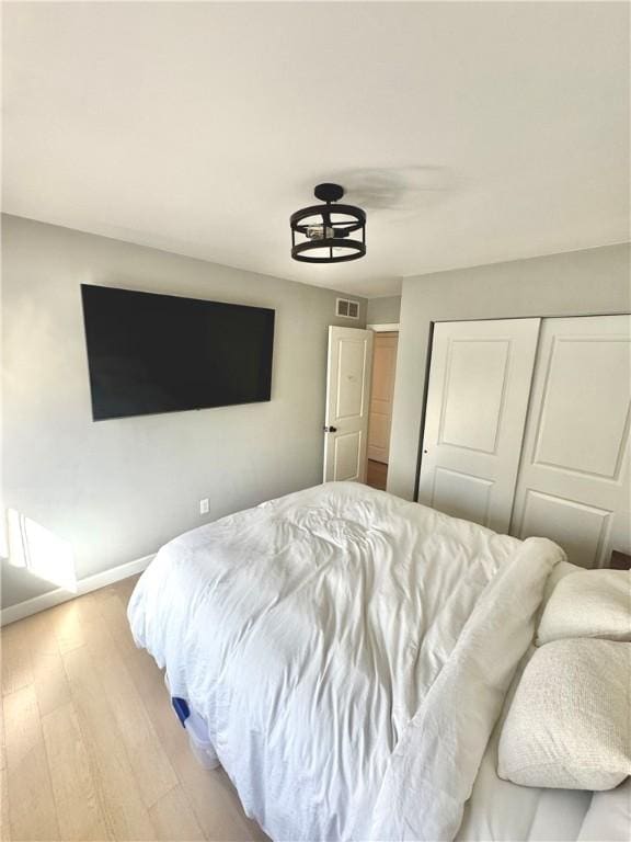 bedroom with a closet, baseboards, visible vents, and light wood-type flooring