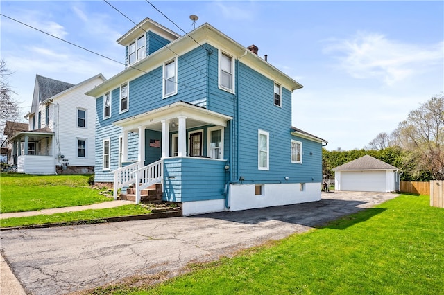 american foursquare style home with a detached garage, fence, a chimney, and a front yard