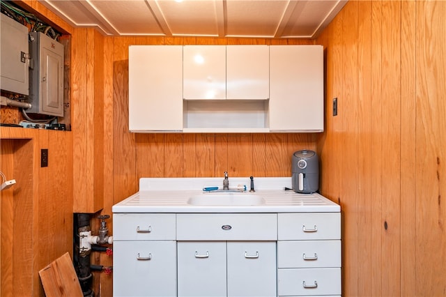laundry area featuring a sink, electric panel, and wooden walls