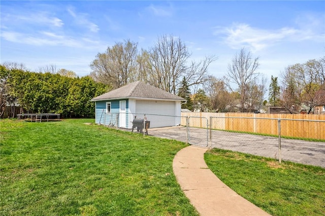 view of yard featuring fence, a detached garage, an outbuilding, and a gate