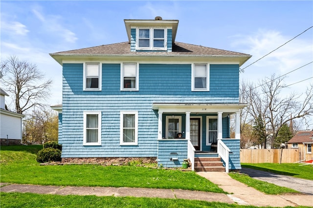 american foursquare style home featuring a front lawn, fence, and covered porch