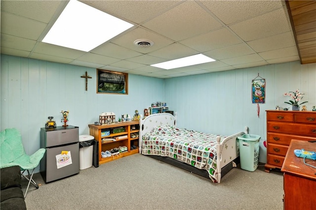carpeted bedroom with freestanding refrigerator, visible vents, and a paneled ceiling