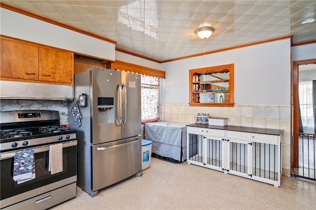 kitchen featuring brown cabinets, crown molding, appliances with stainless steel finishes, wainscoting, and under cabinet range hood