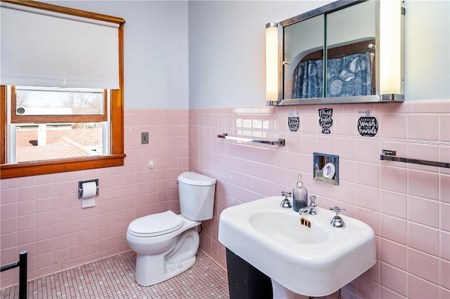 bathroom with tile walls, tile patterned flooring, a sink, a wainscoted wall, and toilet