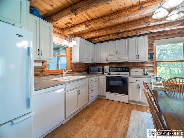 kitchen with a sink, under cabinet range hood, a wealth of natural light, and white appliances