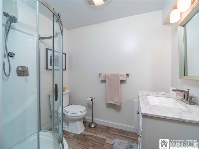bathroom featuring vanity, wood finished floors, toilet, baseboards, and an enclosed shower