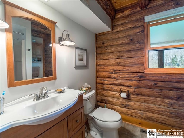 bathroom featuring toilet, log walls, and vanity