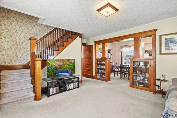 carpeted living area featuring baseboards and stairs