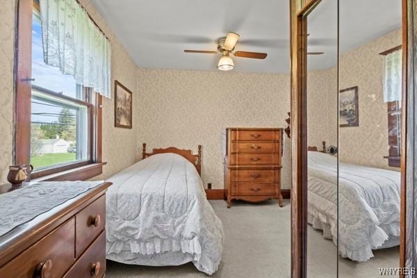 bedroom with light colored carpet, ceiling fan, and wallpapered walls