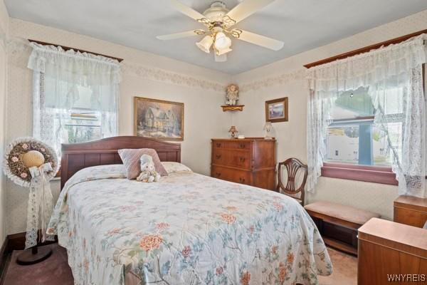 bedroom with a ceiling fan, light carpet, and multiple windows