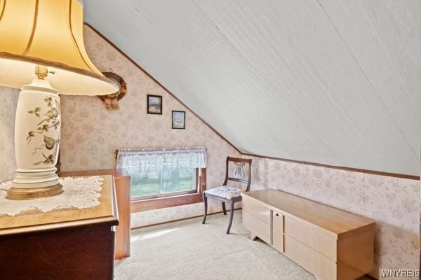 carpeted bedroom with wallpapered walls and lofted ceiling