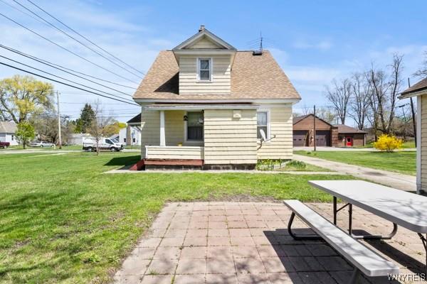 rear view of house featuring a lawn and a shingled roof
