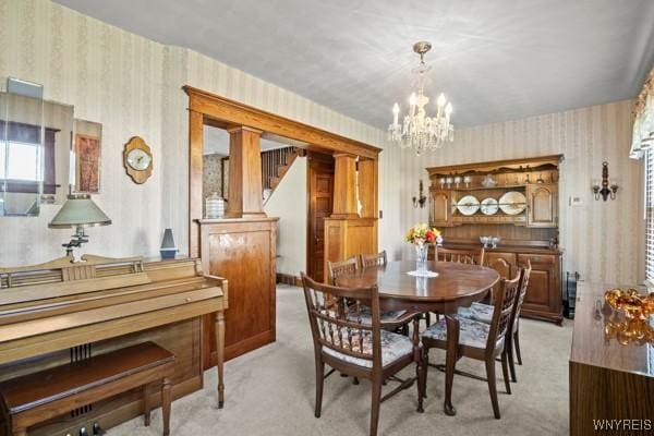 dining area featuring an inviting chandelier, light carpet, and wallpapered walls