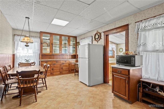 404 72nd St, Niagara Falls, NY 14304 - kitchen featuring freestanding refrigerator, wallpapered walls, black microwave, brown cabinetry, and light countertops