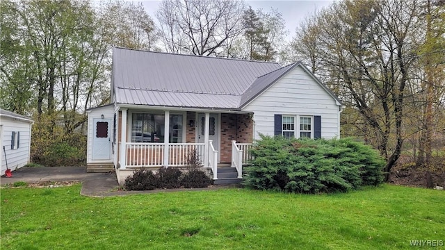 view of front facade with covered porch, metal roof, and a front lawn