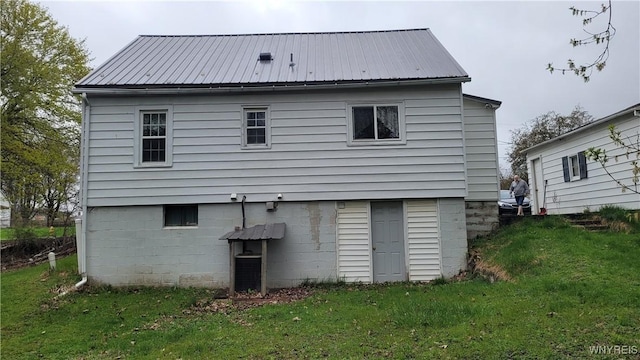 back of house with a lawn and metal roof