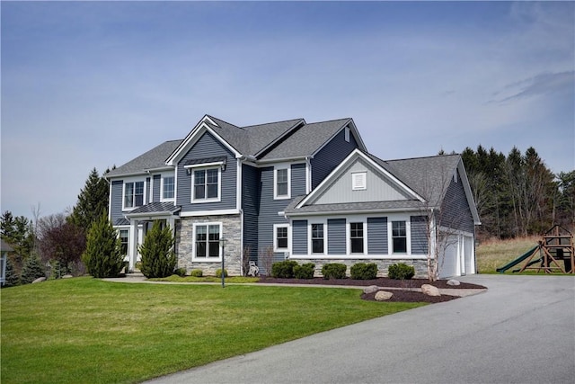 view of front of home with board and batten siding, driveway, stone siding, and a front lawn