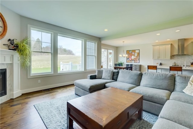 living area featuring an inviting chandelier, a fireplace, wood finished floors, and a wealth of natural light