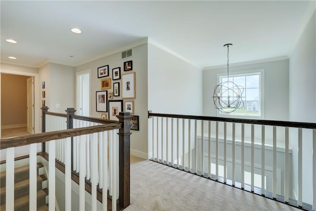 hallway with an inviting chandelier, ornamental molding, visible vents, recessed lighting, and an upstairs landing