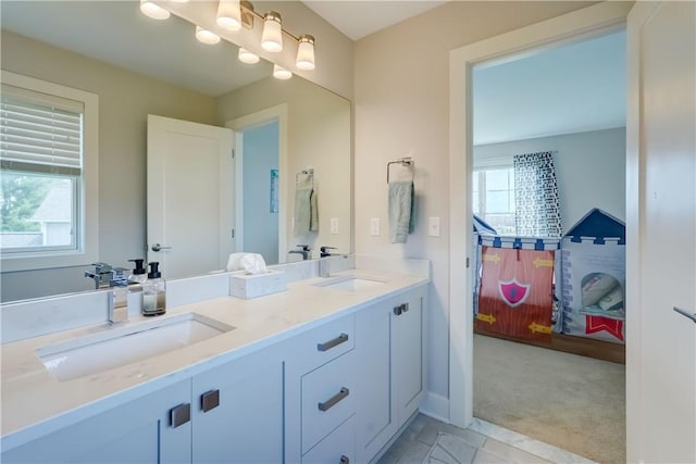 full bathroom with double vanity, a healthy amount of sunlight, and a sink