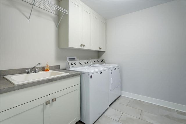 washroom featuring washing machine and dryer, cabinet space, a sink, baseboards, and light tile patterned flooring