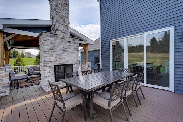 deck featuring an outdoor stone fireplace and outdoor dining space