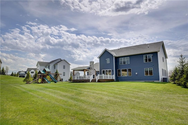back of property with a lawn, a playground, central AC, and a deck